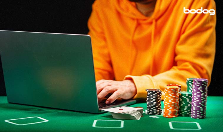 persona con una laptop, fichas y cartas