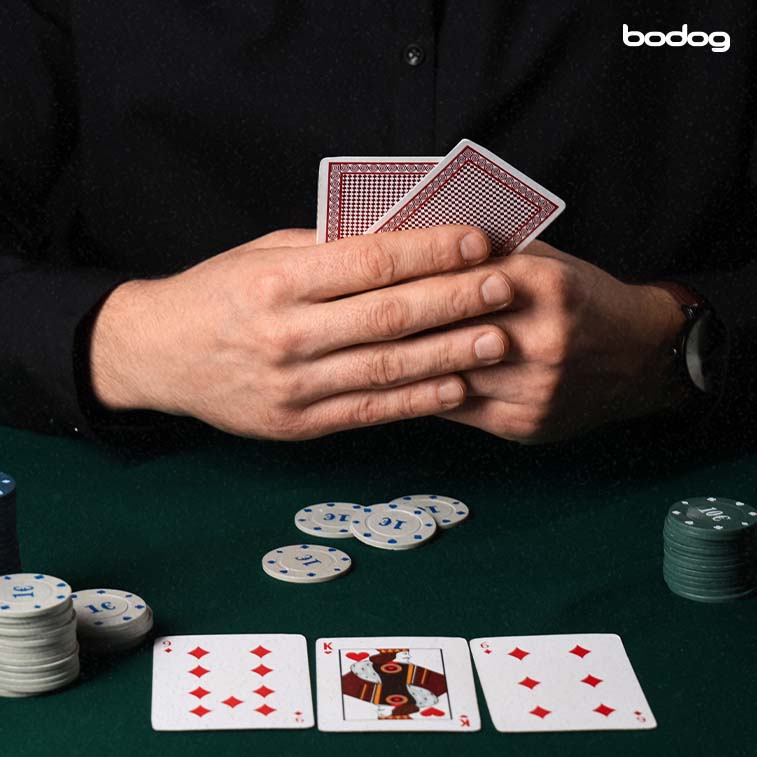 jugador sosteniendo 2 cartas rodeado de fichas