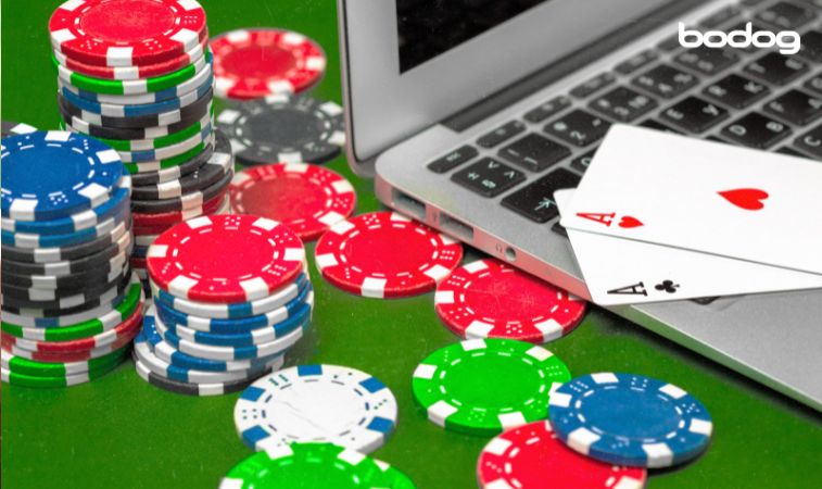 computadora rodeada por fichas de poker y doble de ases